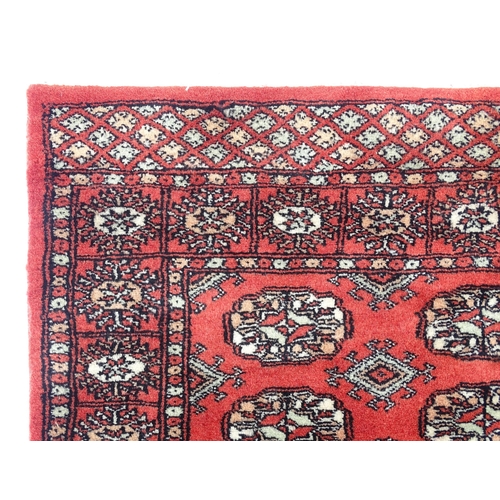 1370 - Carpet / Rug : A Pakistan wool red ground rug decorated with repeating geometric motifs with further... 