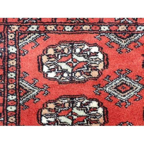 1370 - Carpet / Rug : A Pakistan wool red ground rug decorated with repeating geometric motifs with further... 