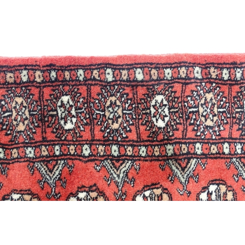 1370 - Carpet / Rug : A Pakistan wool red ground rug decorated with repeating geometric motifs with further... 