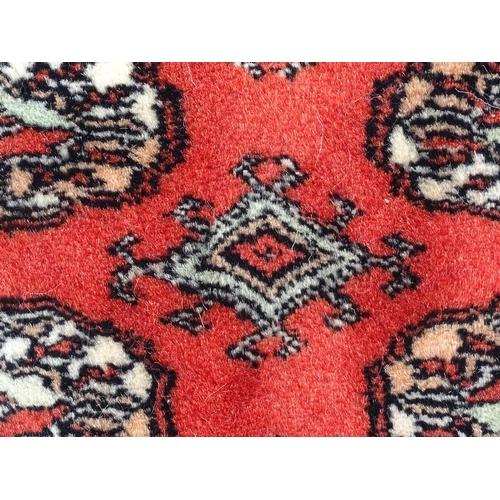 1370 - Carpet / Rug : A Pakistan wool red ground rug decorated with repeating geometric motifs with further... 