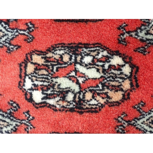 1370 - Carpet / Rug : A Pakistan wool red ground rug decorated with repeating geometric motifs with further... 