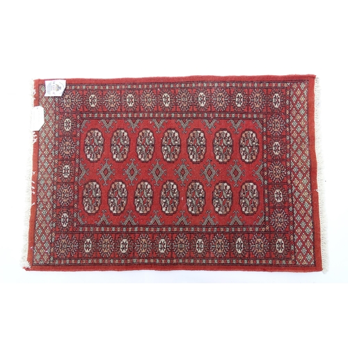 1370 - Carpet / Rug : A Pakistan wool red ground rug decorated with repeating geometric motifs with further... 