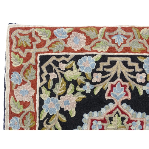 1371 - Carpet / Rug : A black and red ground rug with floral and foliate detail. Approx. 35