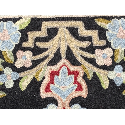 1371 - Carpet / Rug : A black and red ground rug with floral and foliate detail. Approx. 35