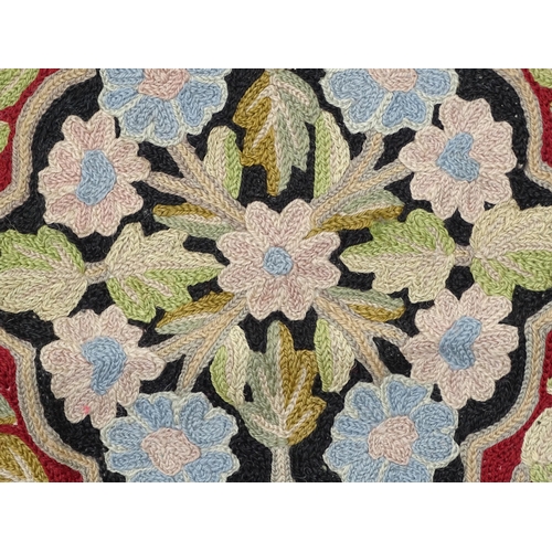 1371 - Carpet / Rug : A black and red ground rug with floral and foliate detail. Approx. 35