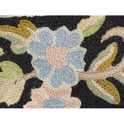 1371 - Carpet / Rug : A black and red ground rug with floral and foliate detail. Approx. 35