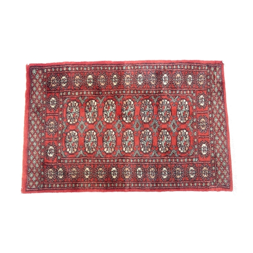 1373 - Carpet / Rug : A Pakistan wool red ground rug decorated with repeating geometric motifs with further... 