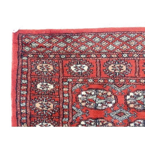 1373 - Carpet / Rug : A Pakistan wool red ground rug decorated with repeating geometric motifs with further... 