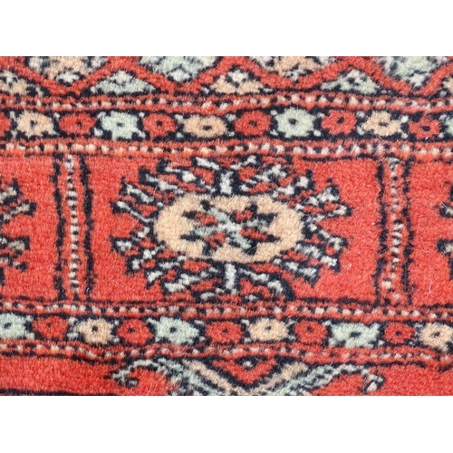 1373 - Carpet / Rug : A Pakistan wool red ground rug decorated with repeating geometric motifs with further... 