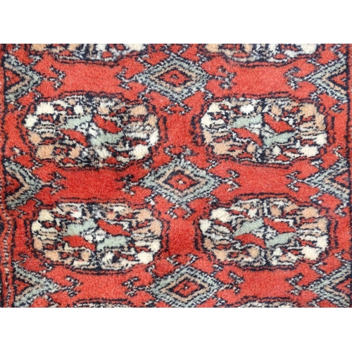 1373 - Carpet / Rug : A Pakistan wool red ground rug decorated with repeating geometric motifs with further... 