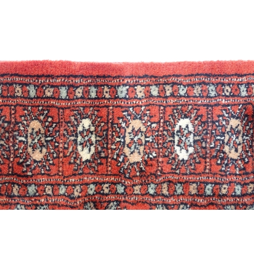 1373 - Carpet / Rug : A Pakistan wool red ground rug decorated with repeating geometric motifs with further... 