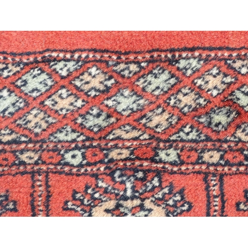 1373 - Carpet / Rug : A Pakistan wool red ground rug decorated with repeating geometric motifs with further... 