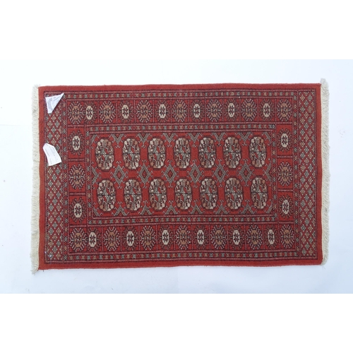 1373 - Carpet / Rug : A Pakistan wool red ground rug decorated with repeating geometric motifs with further... 