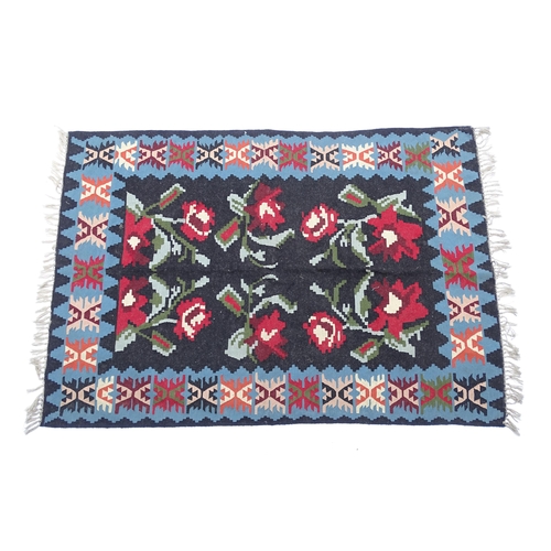 1376 - Carpet / Rug : A black ground rug with red floral decoration, with geometric motifs to borders. Appr... 