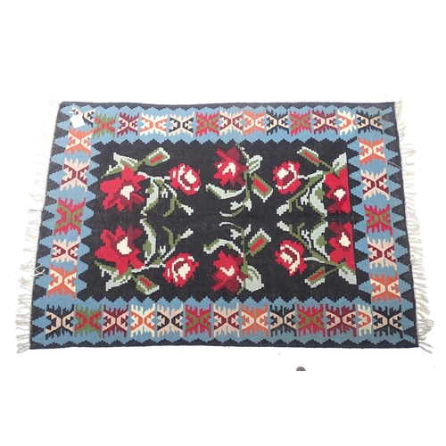 1376 - Carpet / Rug : A black ground rug with red floral decoration, with geometric motifs to borders. Appr... 