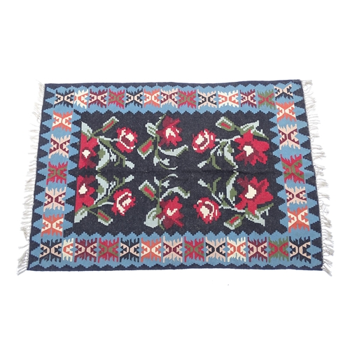 1376 - Carpet / Rug : A black ground rug with red floral decoration, with geometric motifs to borders. Appr... 