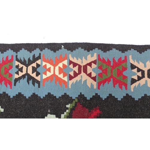 1376 - Carpet / Rug : A black ground rug with red floral decoration, with geometric motifs to borders. Appr... 