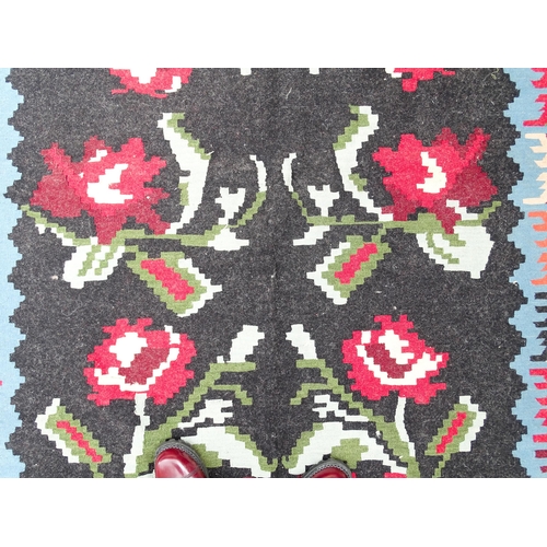 1376 - Carpet / Rug : A black ground rug with red floral decoration, with geometric motifs to borders. Appr... 