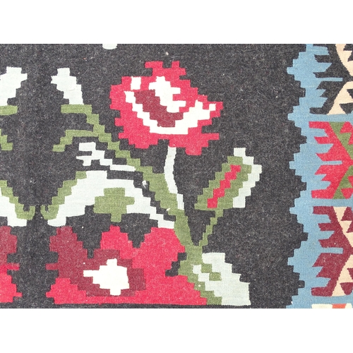 1376 - Carpet / Rug : A black ground rug with red floral decoration, with geometric motifs to borders. Appr... 