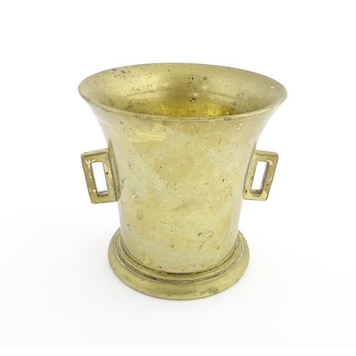 1174 - A 19thC brass pestle and mortar, the mortar of tapering form with twin rectangular handles. Mortar a... 