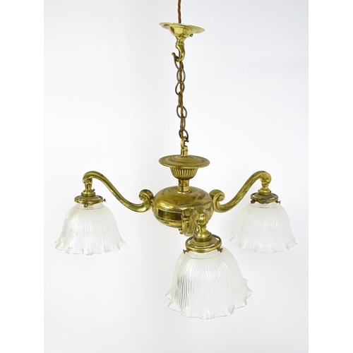 1403 - A pair of brass pendant lights having three scrolling branches with three holophane shades. Approx. ... 