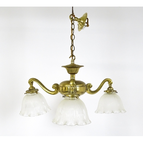 1403 - A pair of brass pendant lights having three scrolling branches with three holophane shades. Approx. ... 