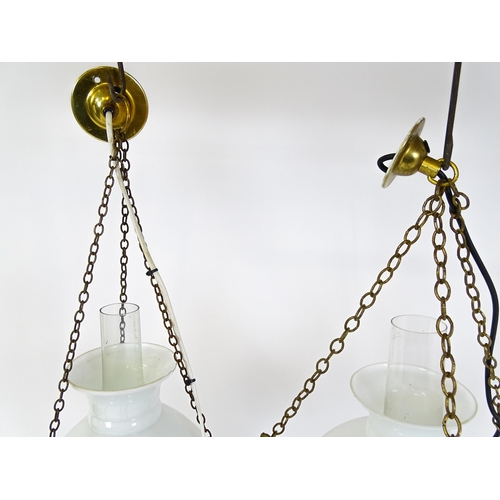 1405 - Two pendant oil lamps one with ceramic reservoir with floral detail. Largest approx. 11