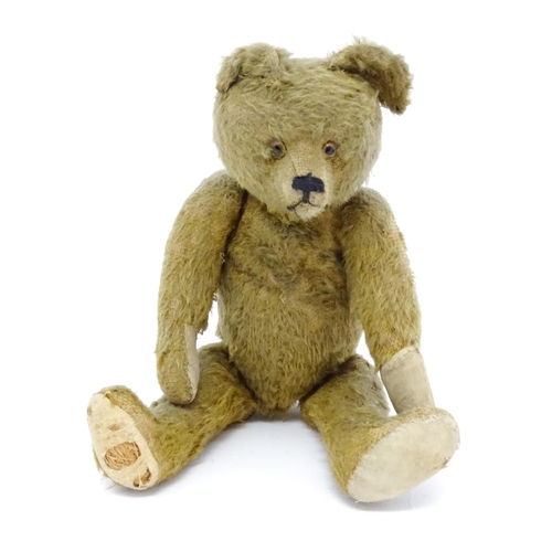 943 - Toy: An early 20thC mohair straw filled teddy bear with proud nose, stitched mouth, hump back, artic... 