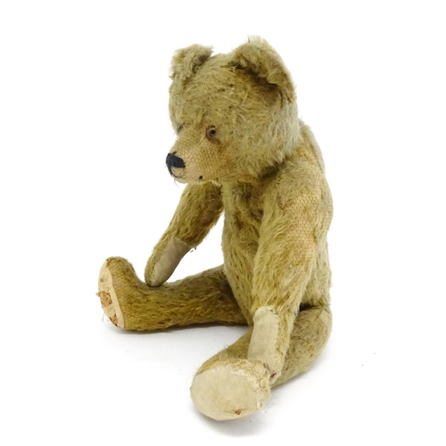 943 - Toy: An early 20thC mohair straw filled teddy bear with proud nose, stitched mouth, hump back, artic... 