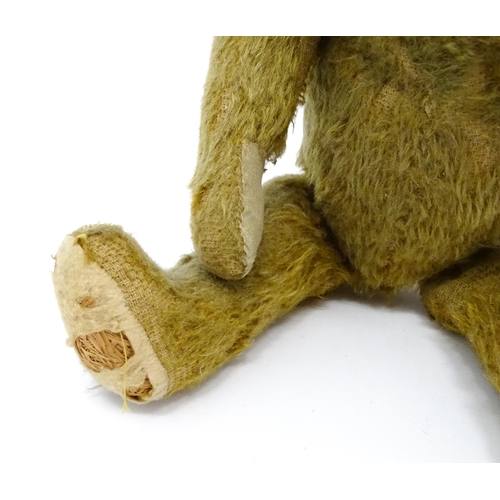 943 - Toy: An early 20thC mohair straw filled teddy bear with proud nose, stitched mouth, hump back, artic... 