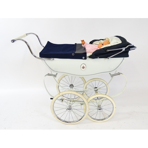 955A - Toys: A 20thC Silver Cross dolls pram with cream exterior. Together with a plastic doll with blinkin... 