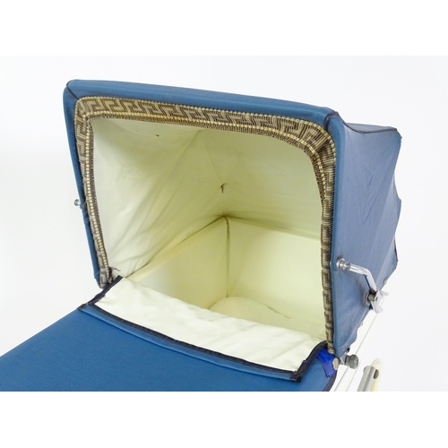 956A - Toys: A 20thC Pedigree dolls pram with cream exterior and blue hood. Together with a plastic doll wi... 