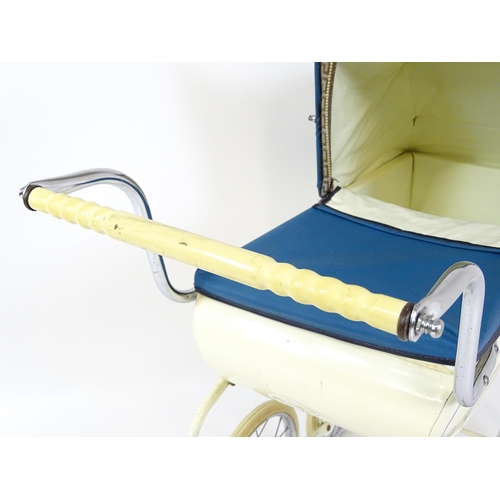 956A - Toys: A 20thC Pedigree dolls pram with cream exterior and blue hood. Together with a plastic doll wi... 