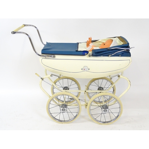 956A - Toys: A 20thC Pedigree dolls pram with cream exterior and blue hood. Together with a plastic doll wi... 