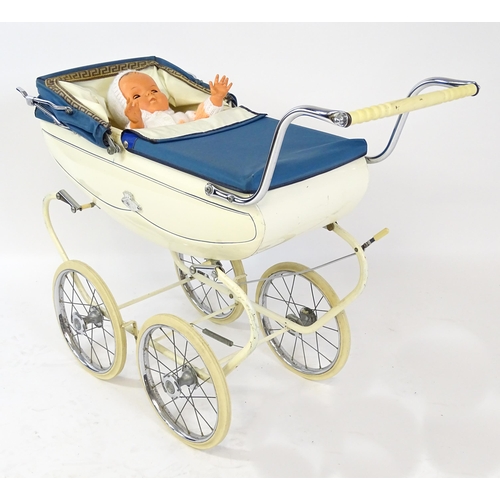 956A - Toys: A 20thC Pedigree dolls pram with cream exterior and blue hood. Together with a plastic doll wi... 