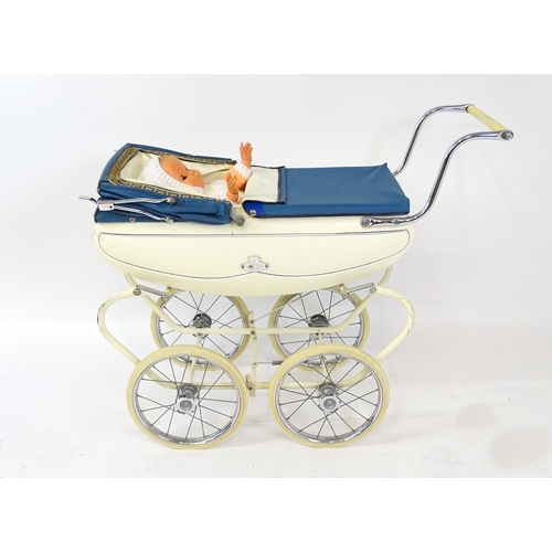 956A - Toys: A 20thC Pedigree dolls pram with cream exterior and blue hood. Together with a plastic doll wi... 