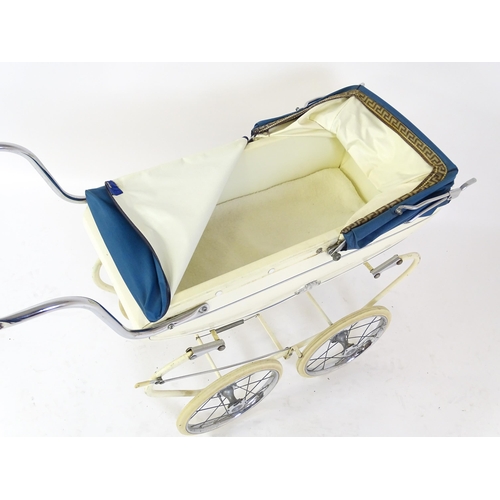 956A - Toys: A 20thC Pedigree dolls pram with cream exterior and blue hood. Together with a plastic doll wi... 