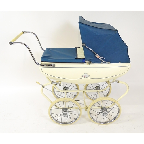 956A - Toys: A 20thC Pedigree dolls pram with cream exterior and blue hood. Together with a plastic doll wi... 