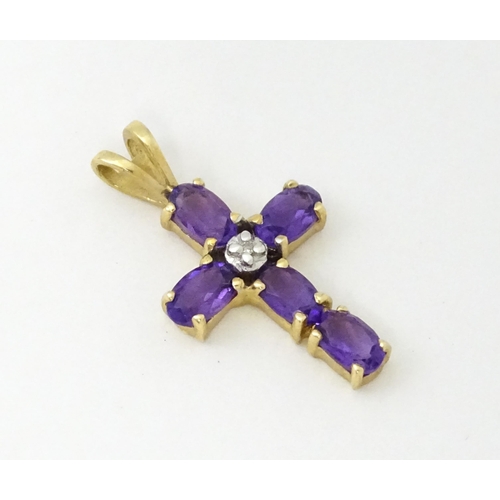 730A - A 9ct gold cross formed pendant set with amethyst and central diamond. Approx. 1