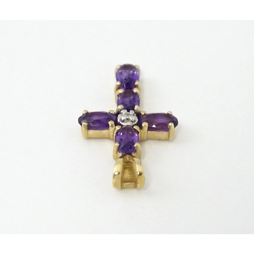 730A - A 9ct gold cross formed pendant set with amethyst and central diamond. Approx. 1