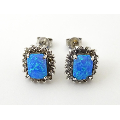 750A - A pair of white metal stud earrings set with central opal bordered by white stones. Approx. 1/2