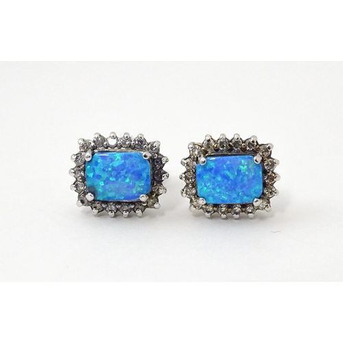 750A - A pair of white metal stud earrings set with central opal bordered by white stones. Approx. 1/2