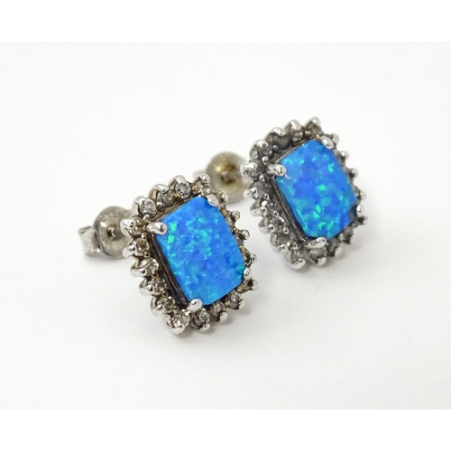 750A - A pair of white metal stud earrings set with central opal bordered by white stones. Approx. 1/2