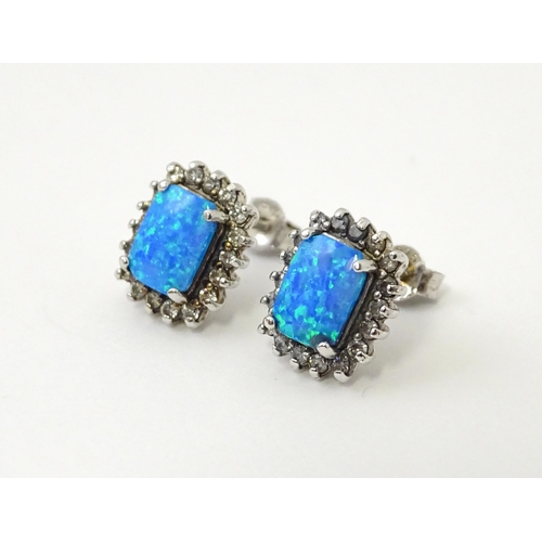 750A - A pair of white metal stud earrings set with central opal bordered by white stones. Approx. 1/2