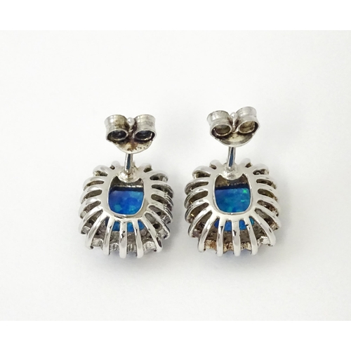 750A - A pair of white metal stud earrings set with central opal bordered by white stones. Approx. 1/2