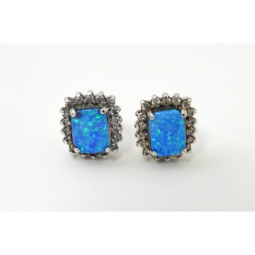 750A - A pair of white metal stud earrings set with central opal bordered by white stones. Approx. 1/2