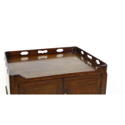 1491 - An 18thC mahogany bedside table / tray top cabinet with a pierced upstand above two hinged doors and... 