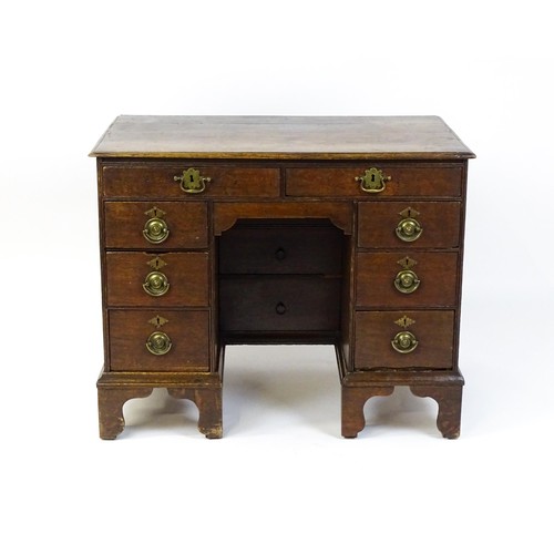 1510 - An early / mid 18thC oak kneehole desk with a moulded top above two short drawers and two banks of f... 