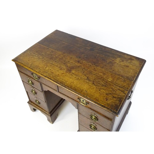 1510 - An early / mid 18thC oak kneehole desk with a moulded top above two short drawers and two banks of f... 