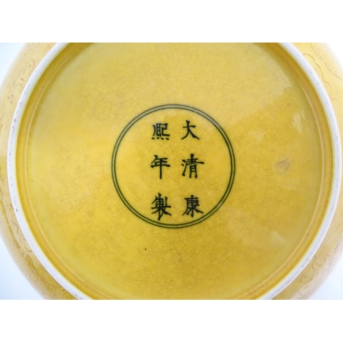 38 - A Chinese dish with a yellow ground decorated with dragons amongst stylised clouds. Character marks ... 